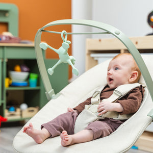 Glückliches Baby mit Silikonspielzeug in der Wippe